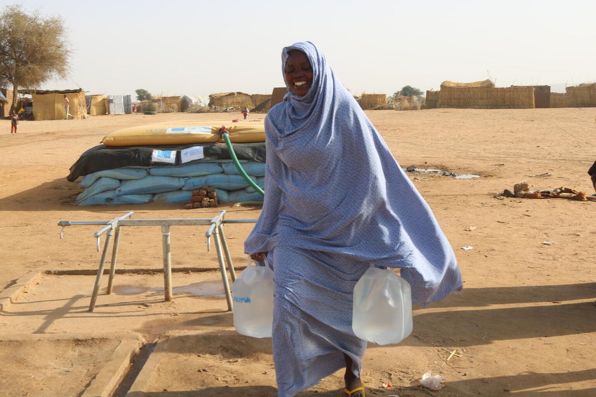 A women carrying water buckets with red sand