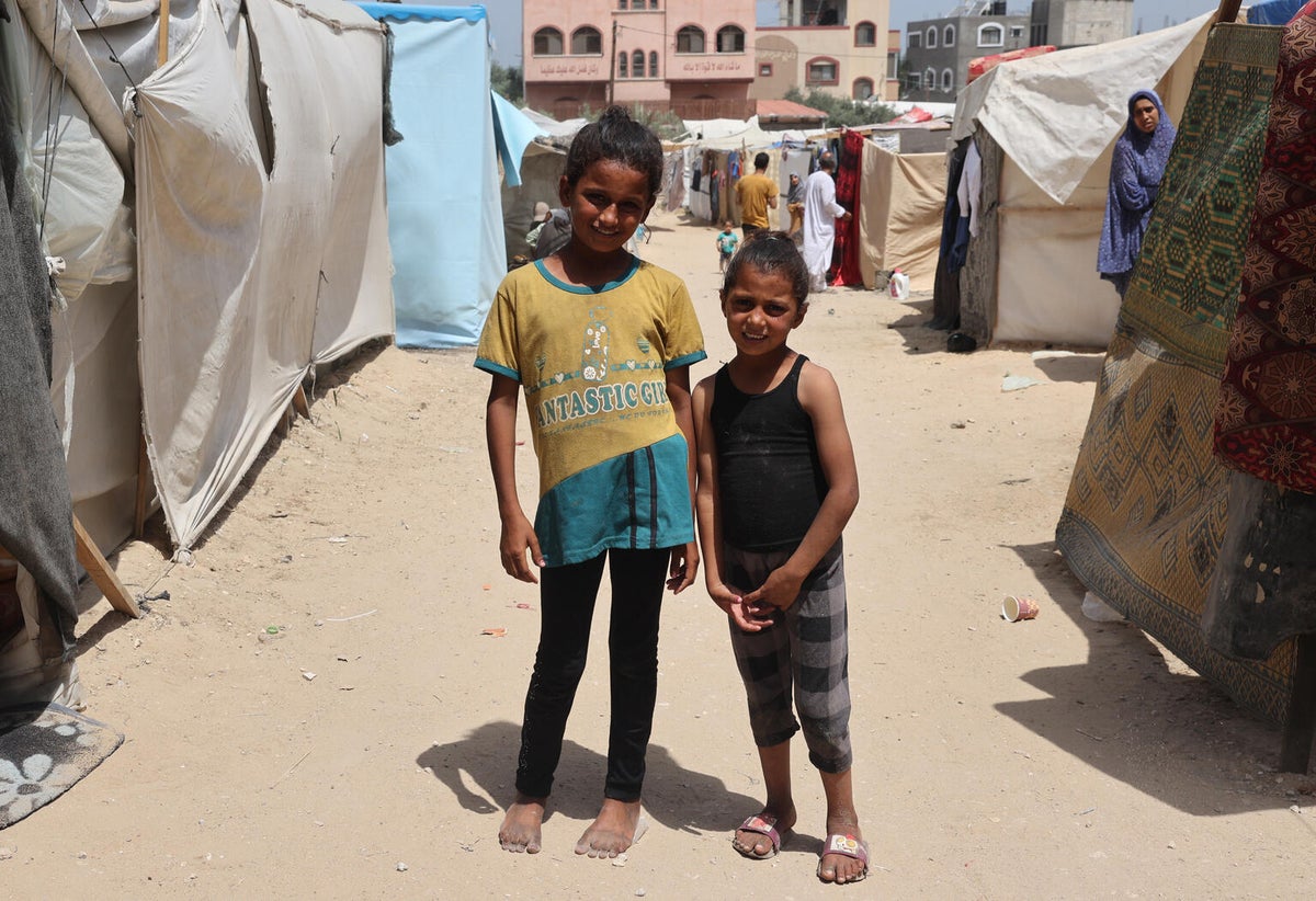 Two young sisters stand in a camp for internally displaced persons in the Gaza Strip.