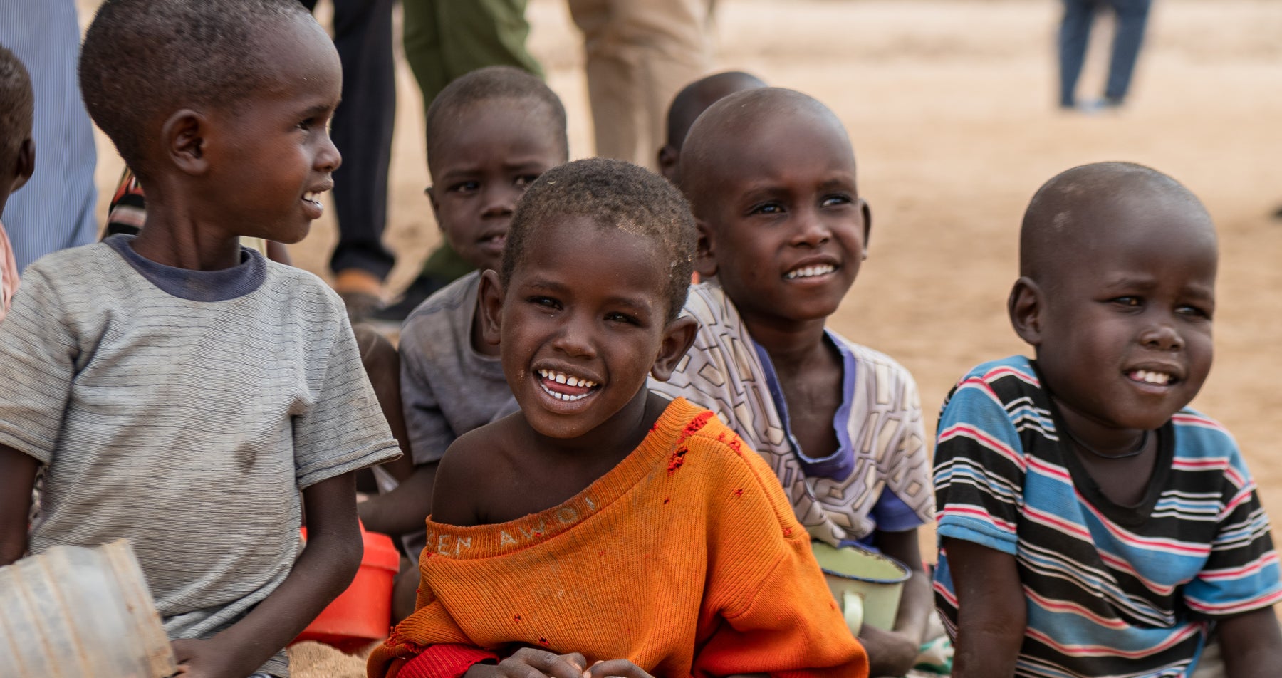 Child in orange shirts sits smiles at camera