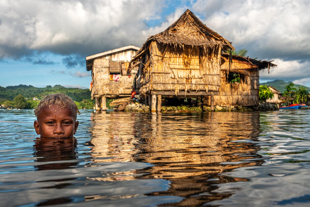 In Solomon Islands, a young boy is swimming in the rising waters during high tide.