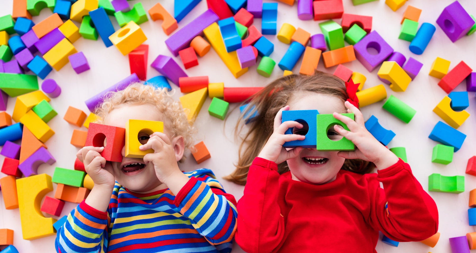 Two young children play with colourful blocks.
