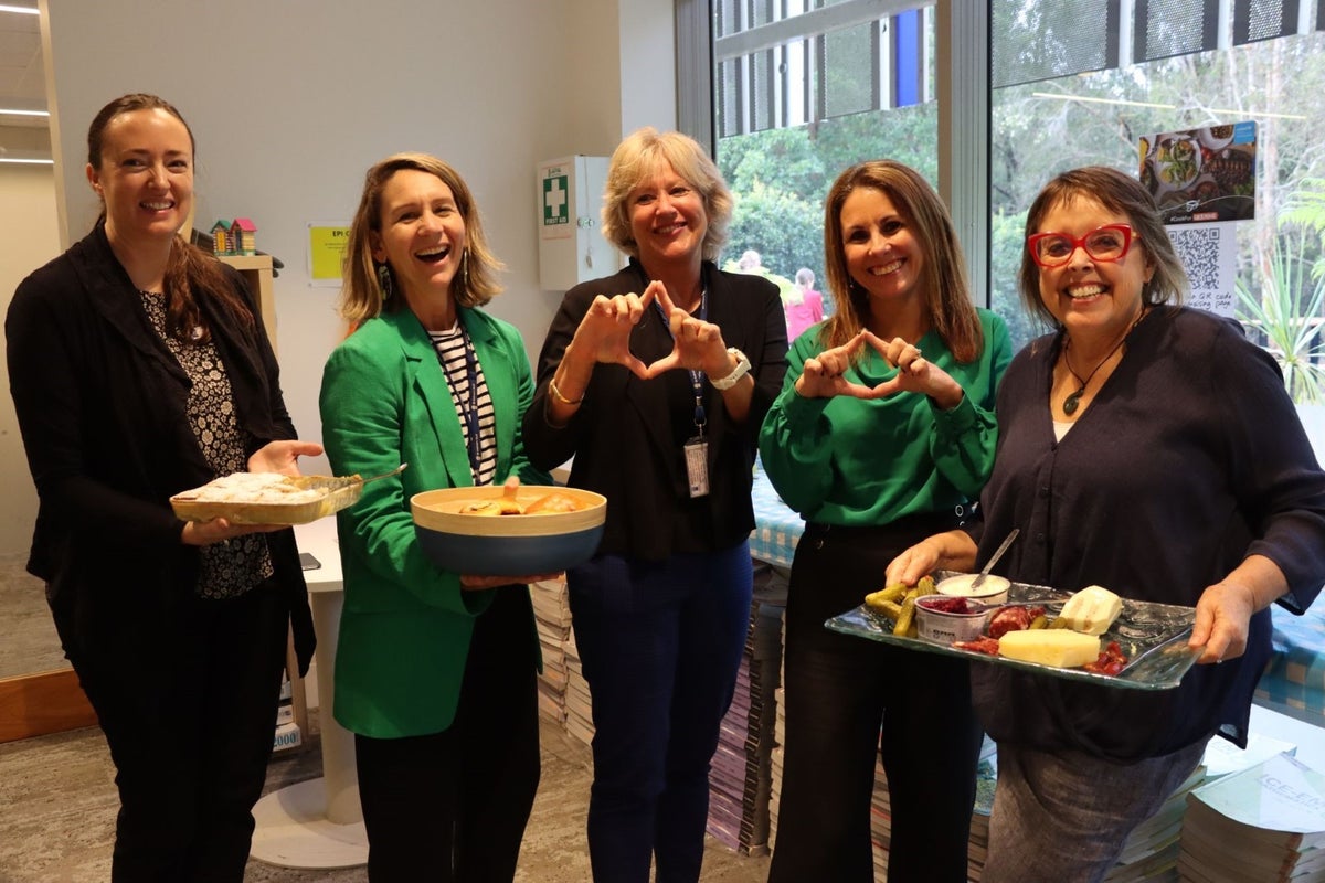 A group of women holding plates of food at a school fundraiser for Ukraine. 