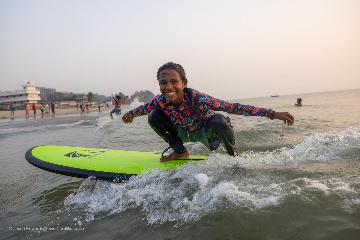 A young girl proudly showing her surfing skills. 