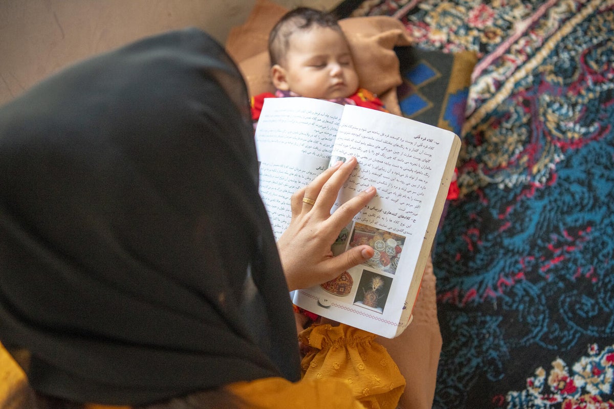 A 17-year-old reads while her baby sleeps.