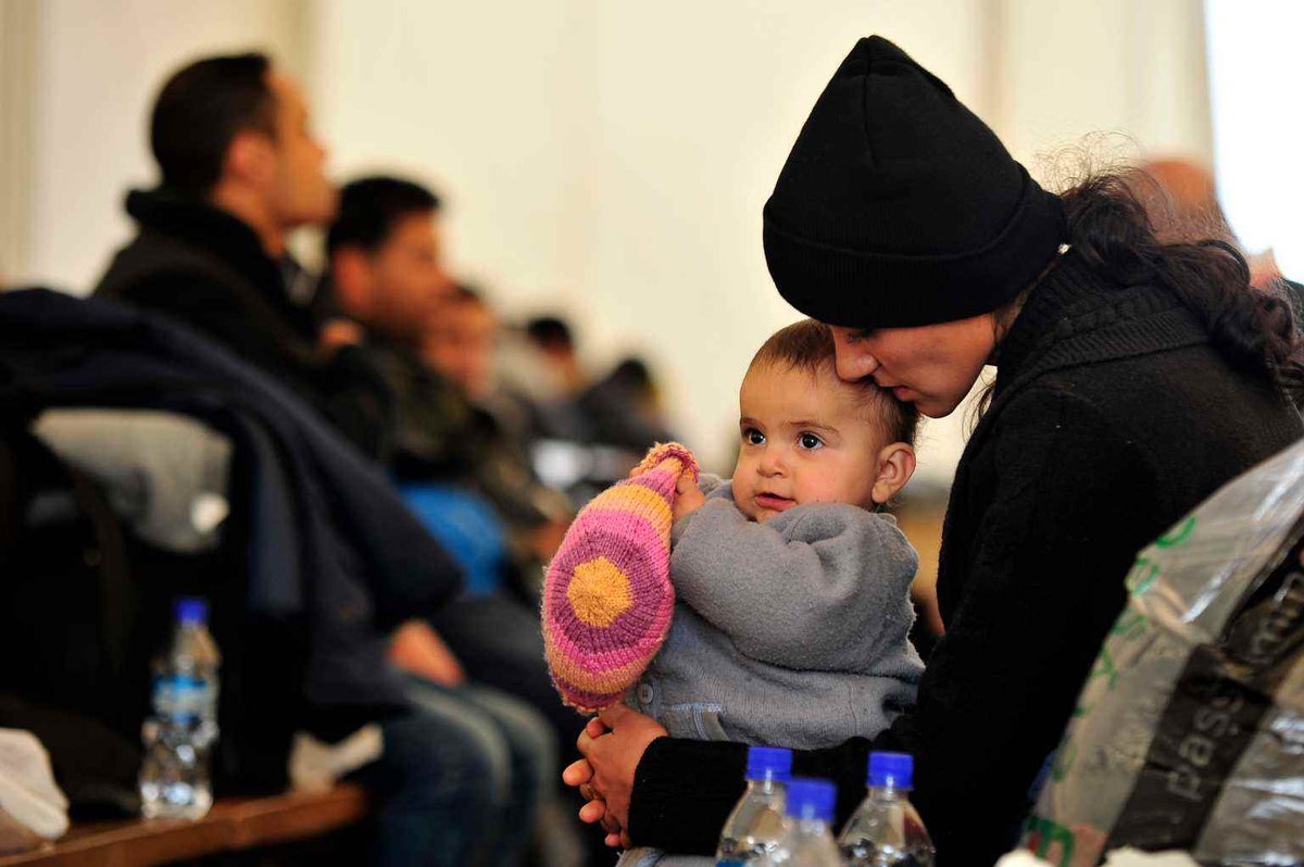 A mother cradles her daughter as they wait at a migrant transit centre to board a train to the border of Serbia and Macedonia in 2015. 