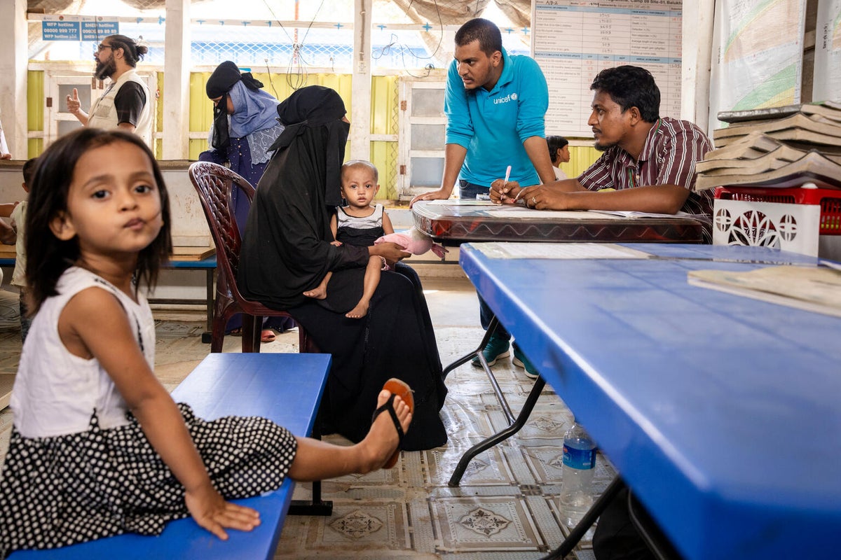 A woman holds her two-year-old daughter  as a volunteer explains her daughter’s growth chart during a regular check-up at a UNICEF-supported integrated nutrition facility.