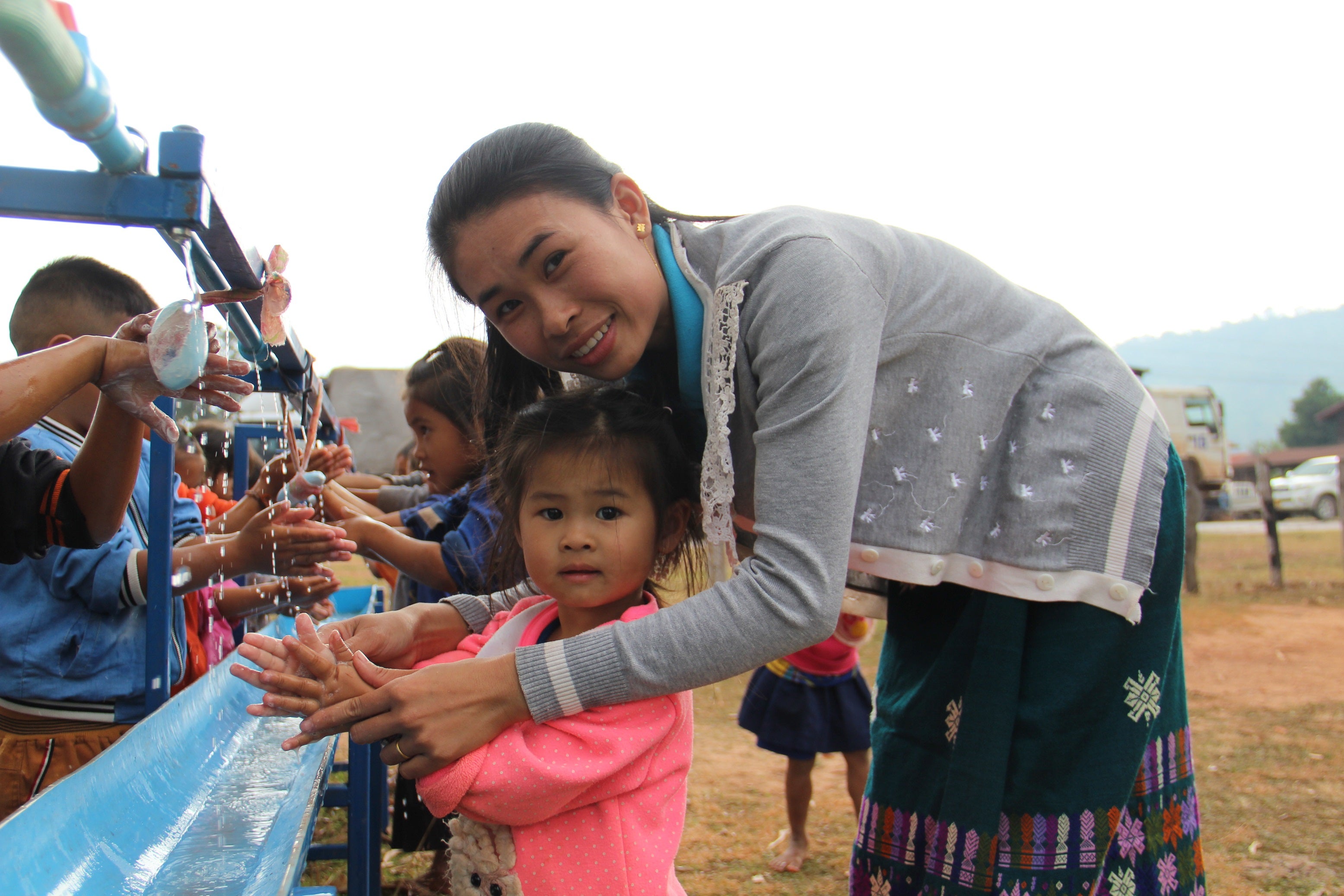 A teacher helping students wash their hands
