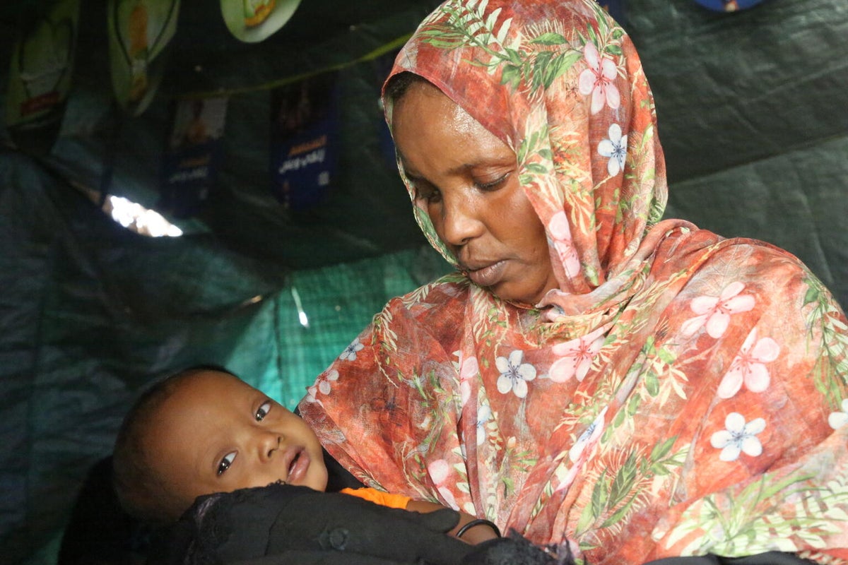 A woman holds her 13-month-old son at her home in Sudan. 