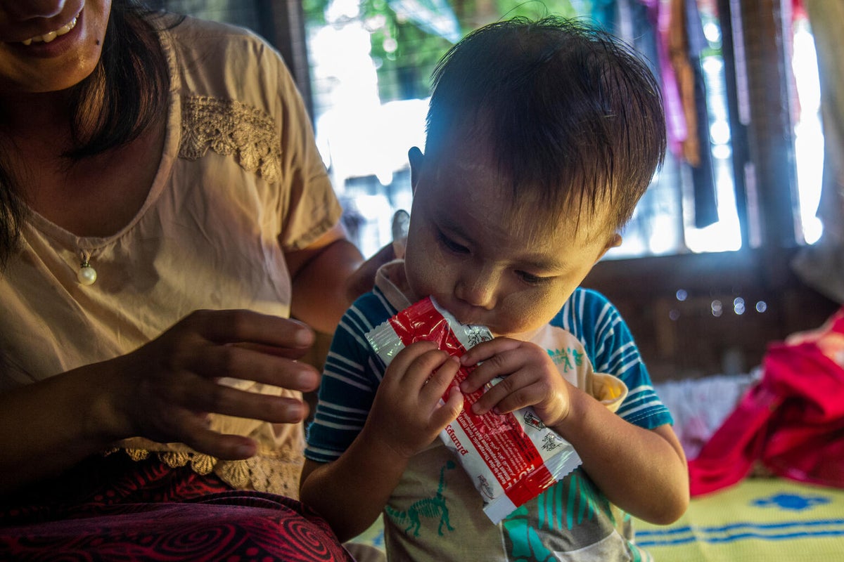 Nyein watches as her daughter, Shi, eats therapeutic food provided with UNICEF support.
