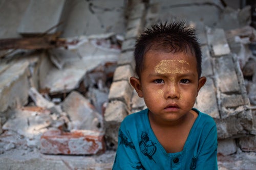 A young boy sits among the rubble of a collapsed building damaged by the magnitude 7.7 earthquake in Myanmar.