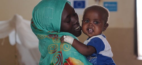 Child being held in their mothers' arms while in hospital