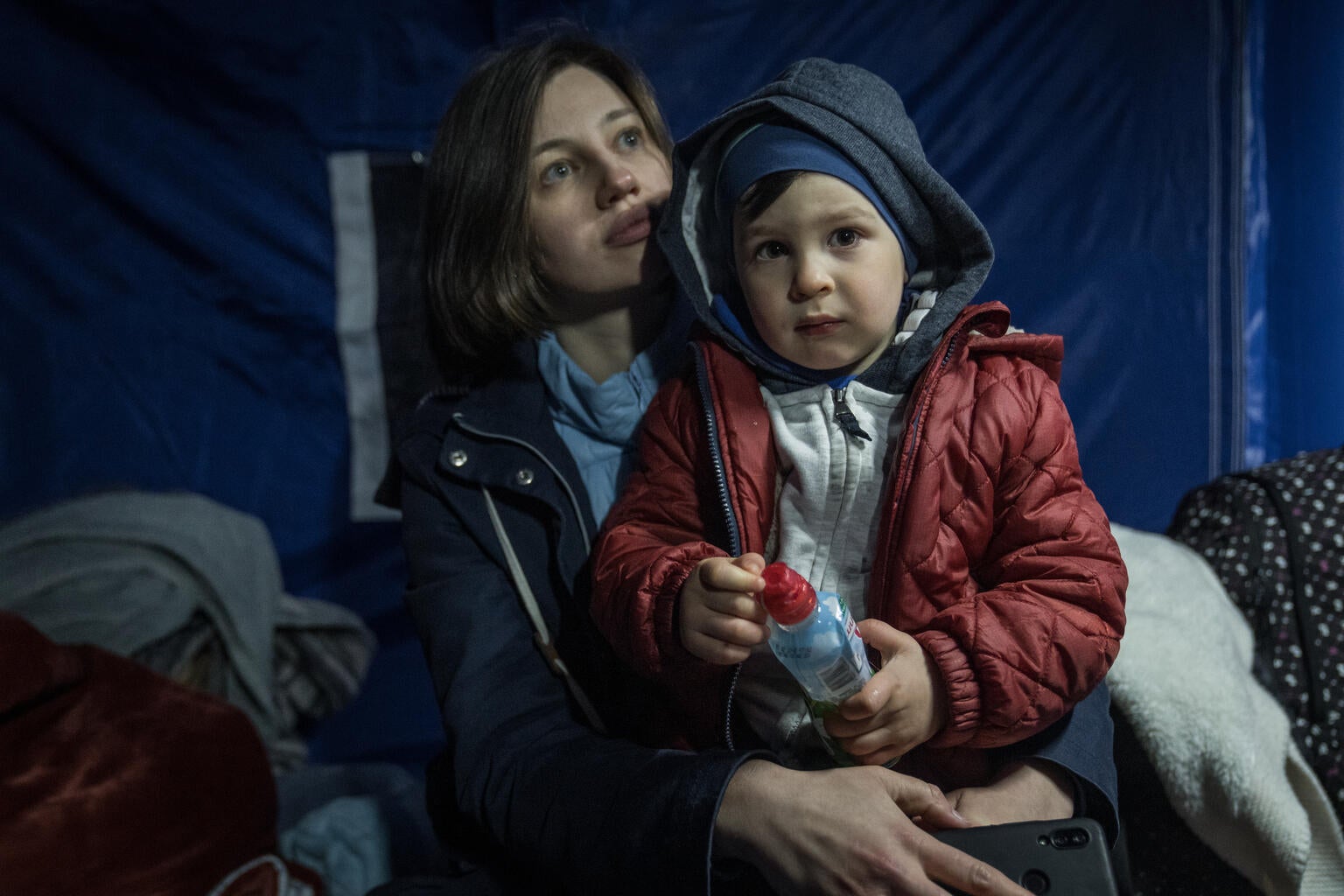 A young girl stands in front of her damaged home in Ukraine.