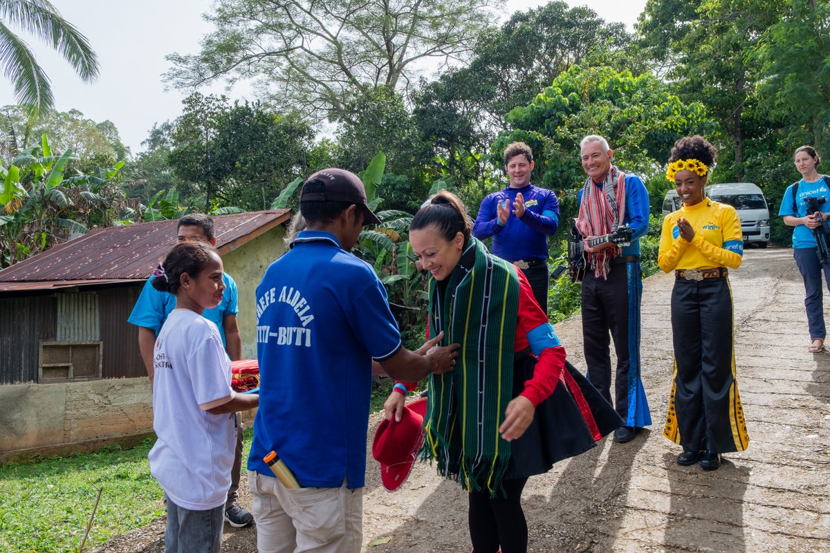 A woman receiving a handwoven fabric over her neck. 