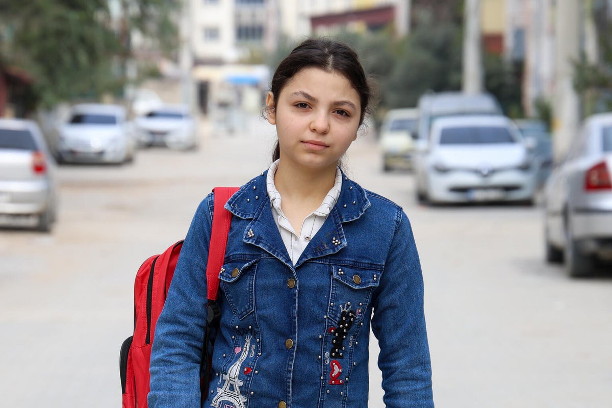 A teenage girl with her backpack standing in the middle of a street. 
