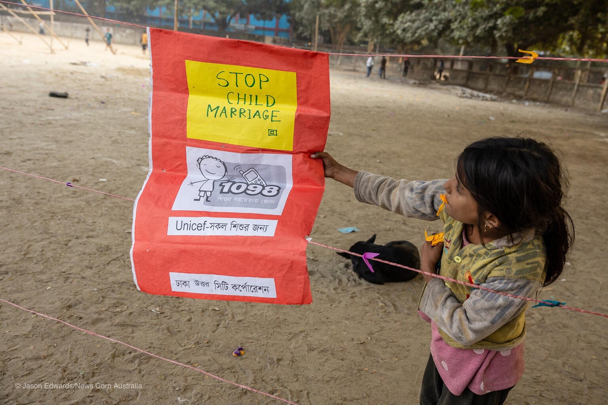A little girl holds a sign against child marriage.