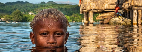 A boy is seen in the rising waters during high tide in a village in the Solomon Islands.