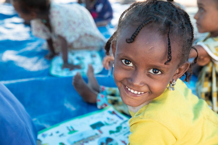 A young girl smiles to the camera.