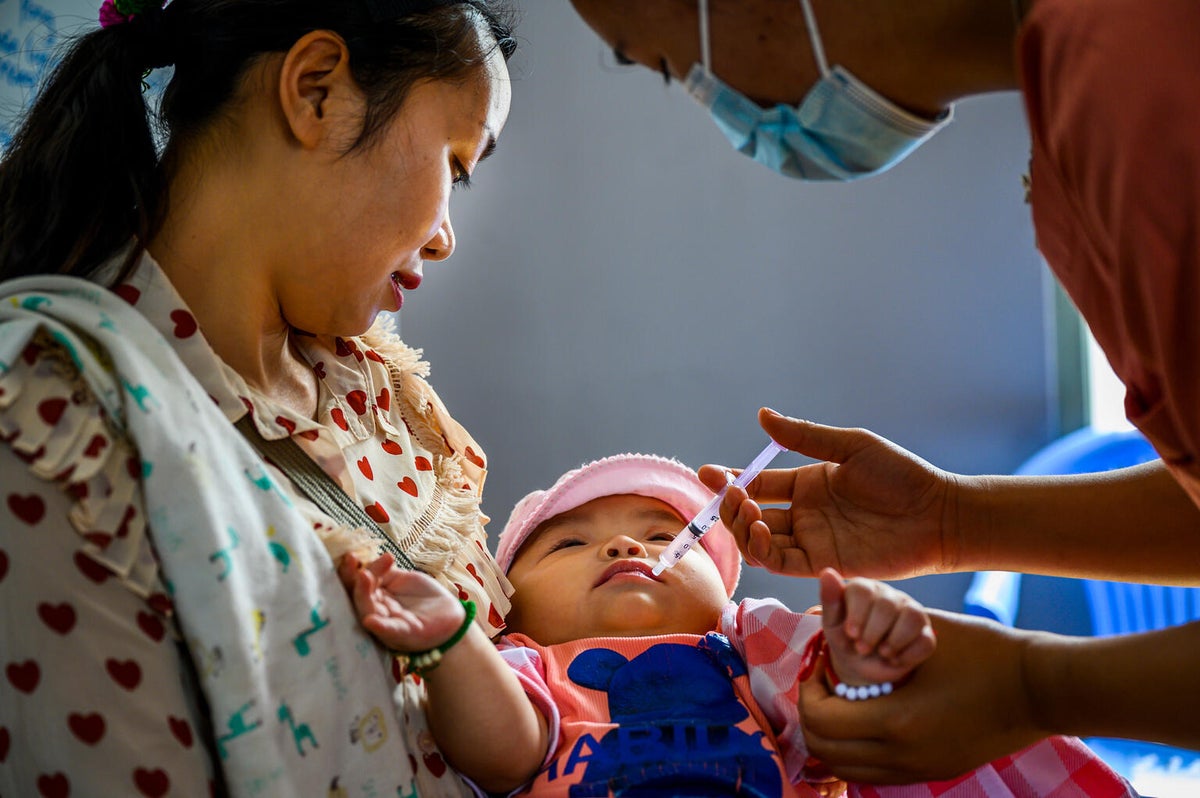 In a remote, hard-to-reach village, a health worker provides a baby with a vaccine during a UNICEF-supported vaccine campaign.