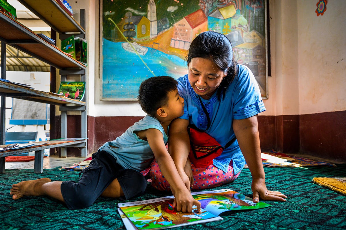 A mother reads a story book to her five-year-old son at a UNICEF-supported learning hub.