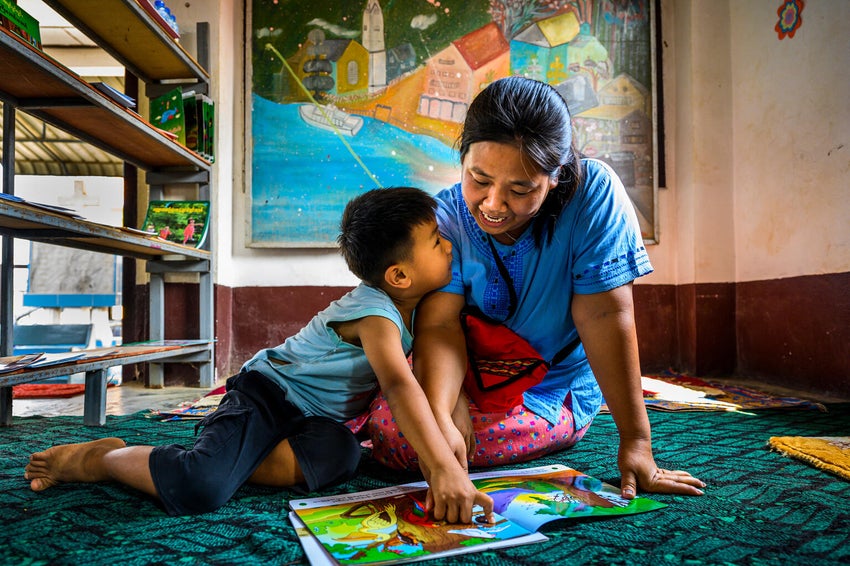 A mother reads a story book to her five-year-old son at a UNICEF-supported learning hub.