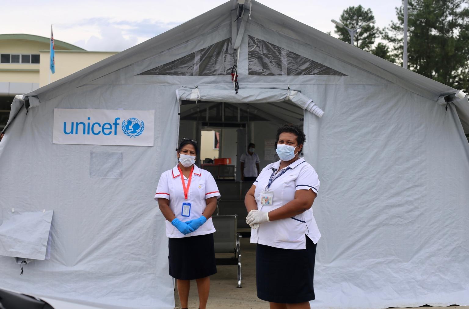 Public Health Nakasi Health Centre and her colleague standing front a fever clinic. 