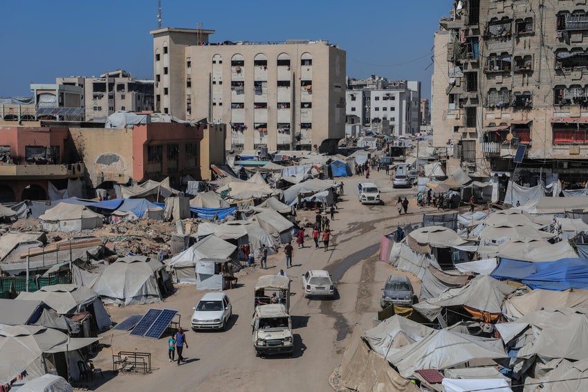 Displaced families build temporary shelters alongside destroyed buildings in the streets of Gaza. 