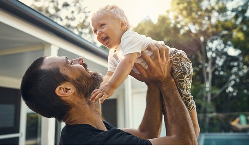A father holds his young son up into the air.