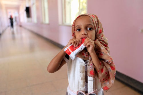 Small girl eating plumpy nut while being treated for malnutrition.