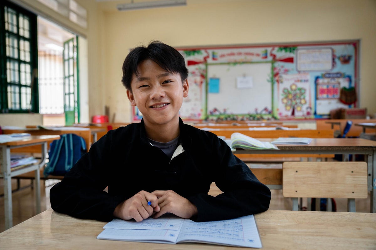 A young boy smiling in a classroom. 