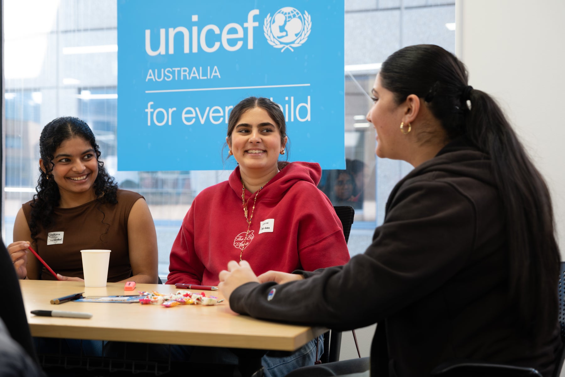 A group of three girls talk and laugh during an LCOY hosted by UNICEF Australia in their Sydney office. 