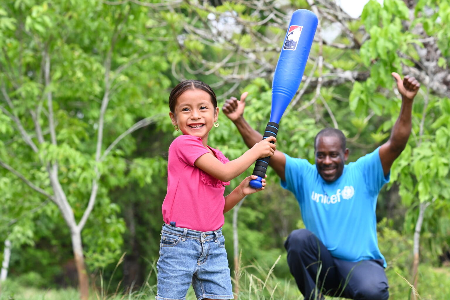 A young girl holding a cricket bat.