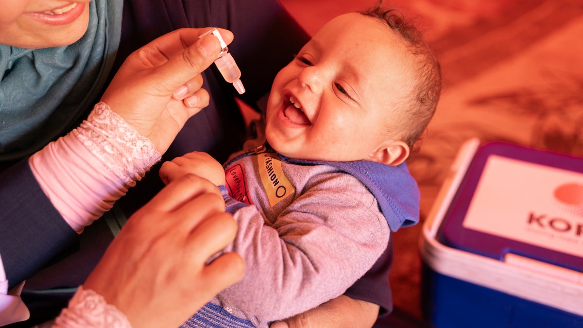 A baby boy receives his measles, mumps, rubella and polio vaccine from a health worker during mobile immunisation.