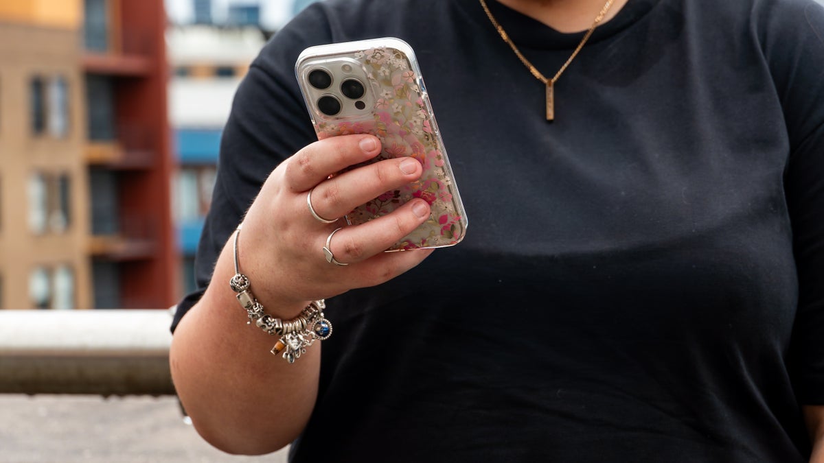A young woman holds her phone.