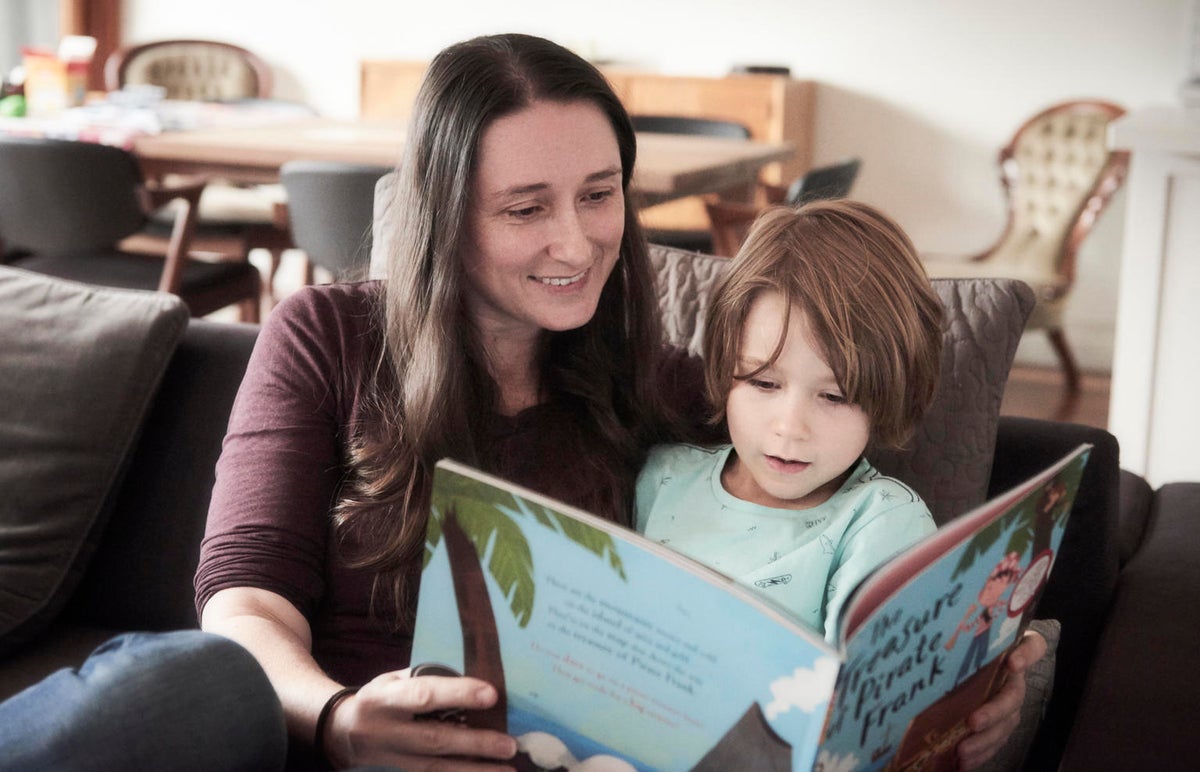 A woman and a boy are looking at a book together.