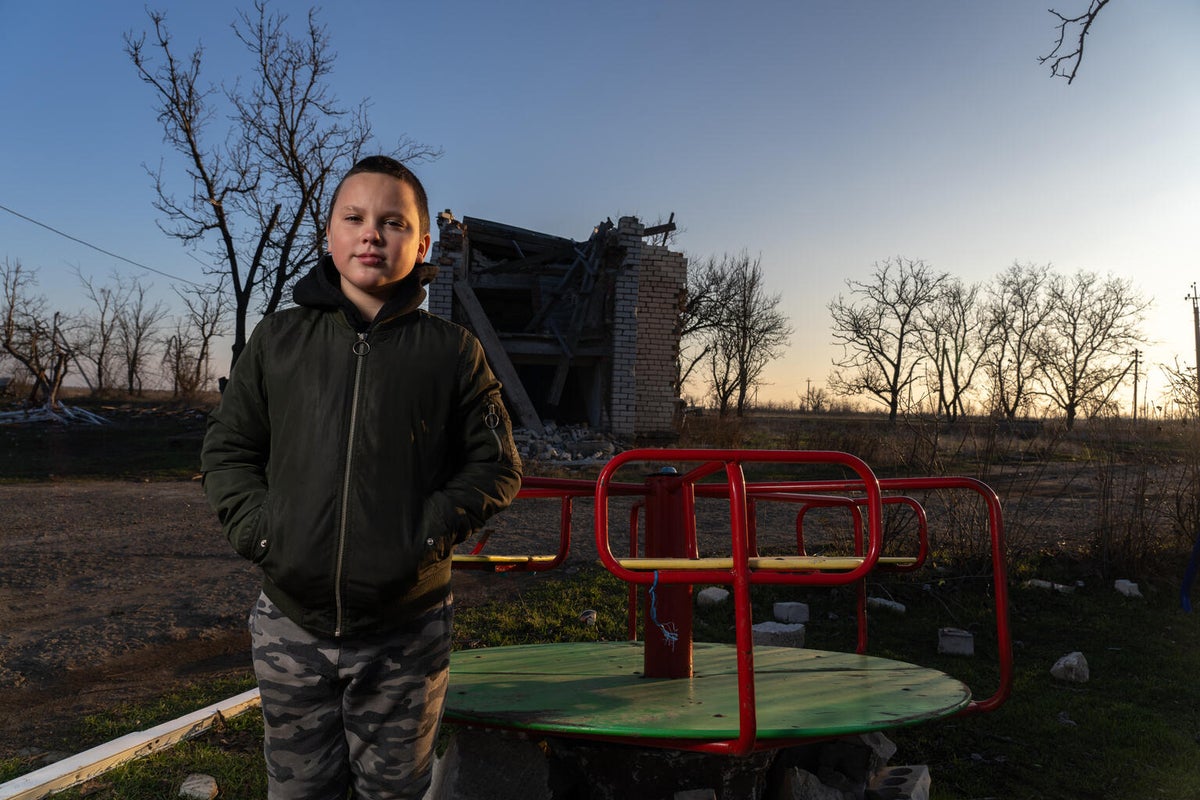 11-year-old Timofii stands in front of the ruins of the kindergarten he once attended. 