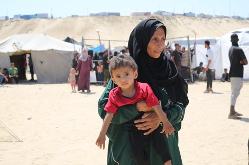 Mother and child sit outside their tent at a camp for internally displaced people in Gaza.