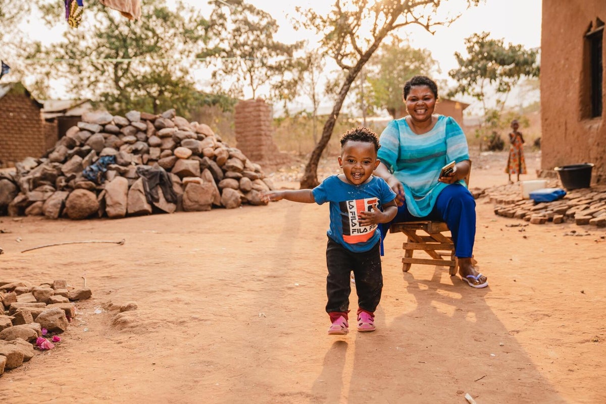A one-year-old, who recovered from mpox at a UNICEF-supported hospital, joyfully plays with his mother outside their home in the DRC. 