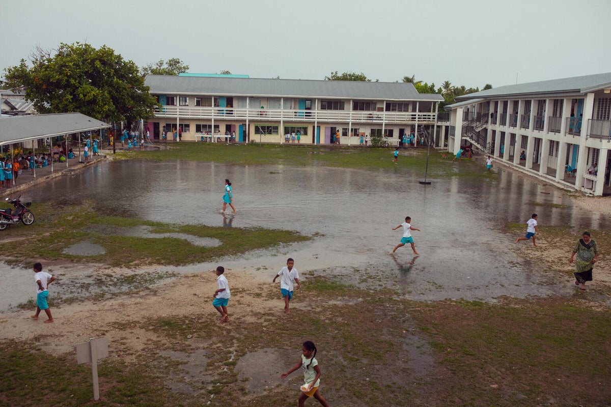 Students wade through the flooded schoolyard in Tuvalu. 