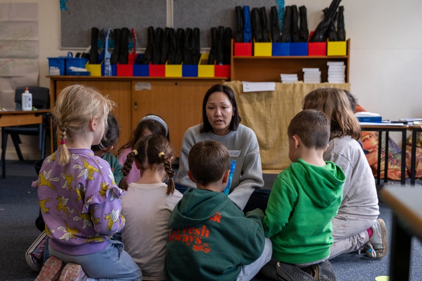 An adult facilitator speaks to a group of young children in a classroom.