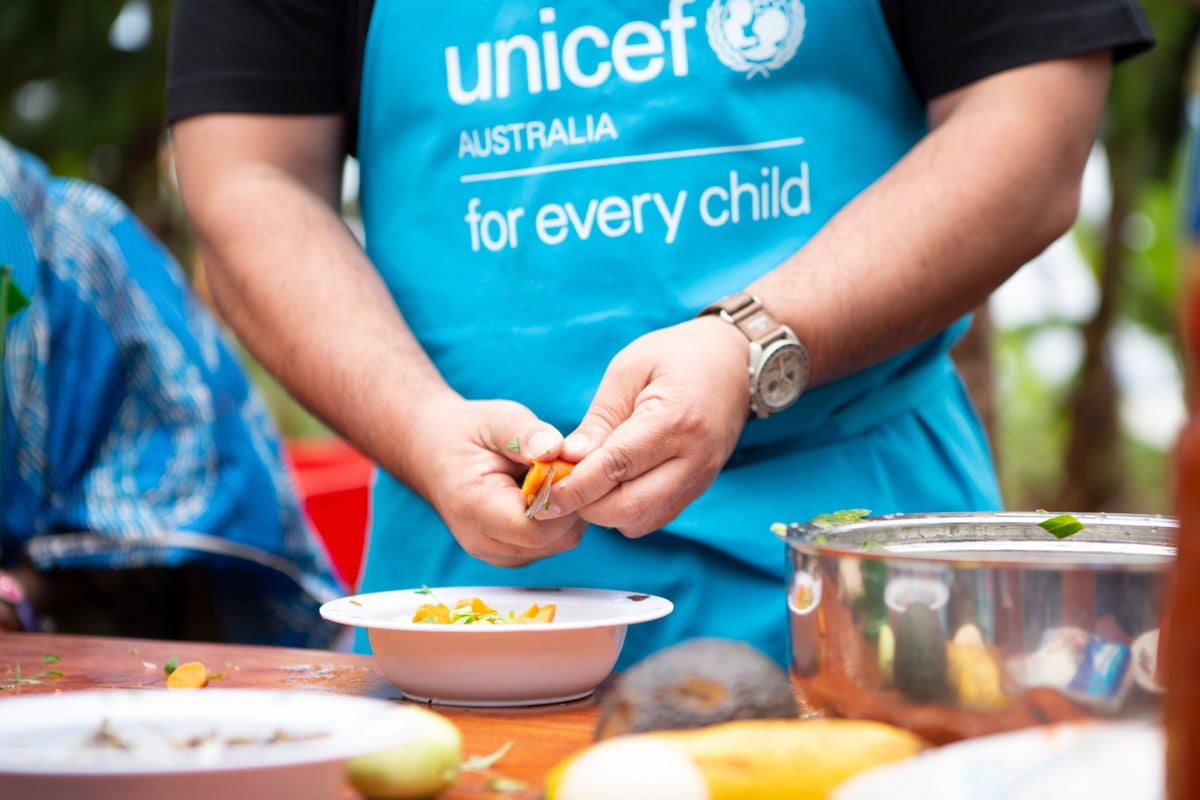 A pair of hands slicing a vegetable into a bowl.