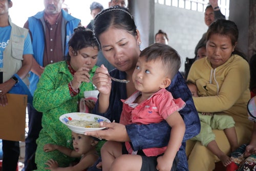 A mother feeds her child during a malnutrition community information session in Cambodia. 