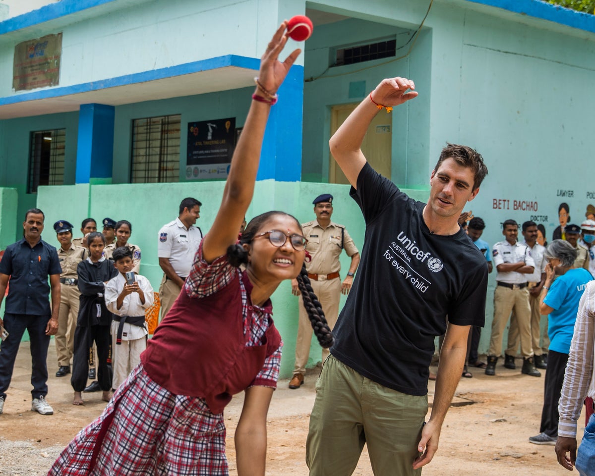 Pat Cummins shows a schoolgirl how to bowl during a game of cricket. 