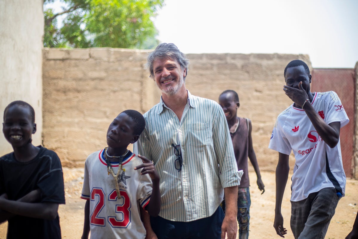 A smiling man with a group of teenagers. 