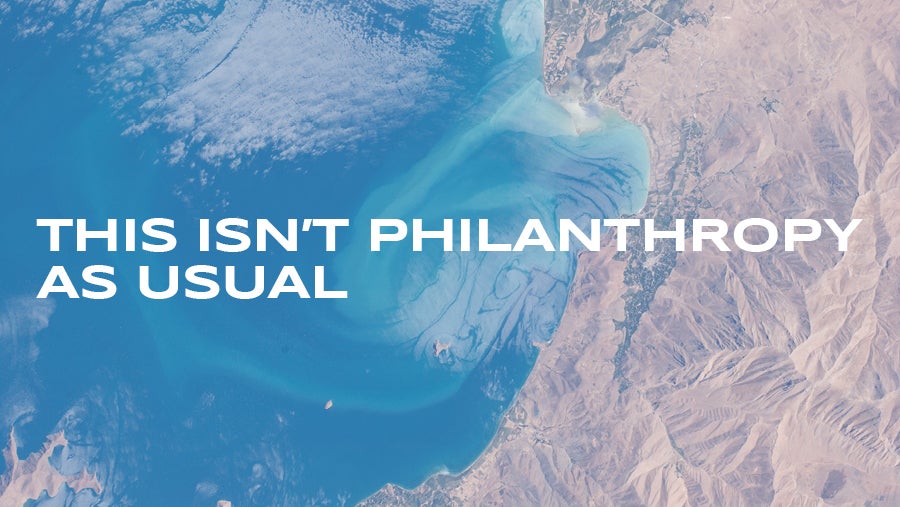 An overhead view or mountains and ocean with the words 'This isn't philanthropy as usual' overlaid