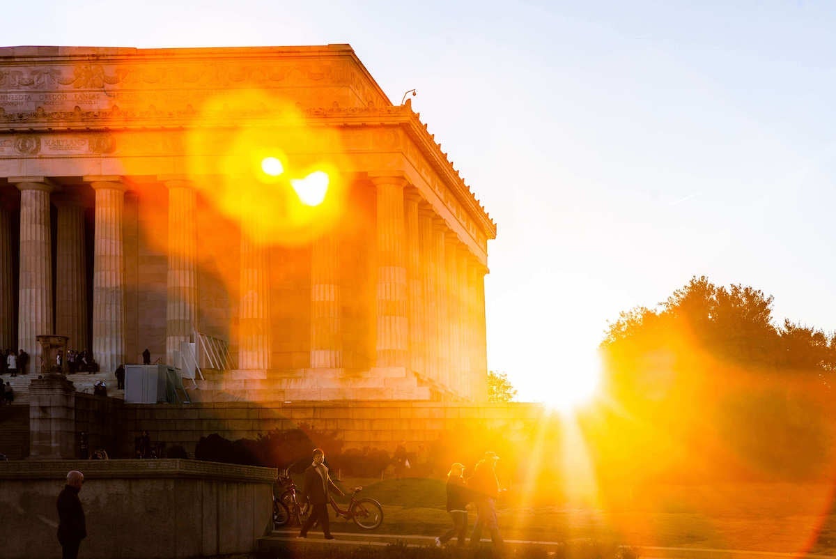 The sun rises behind the Lincoln Memorial