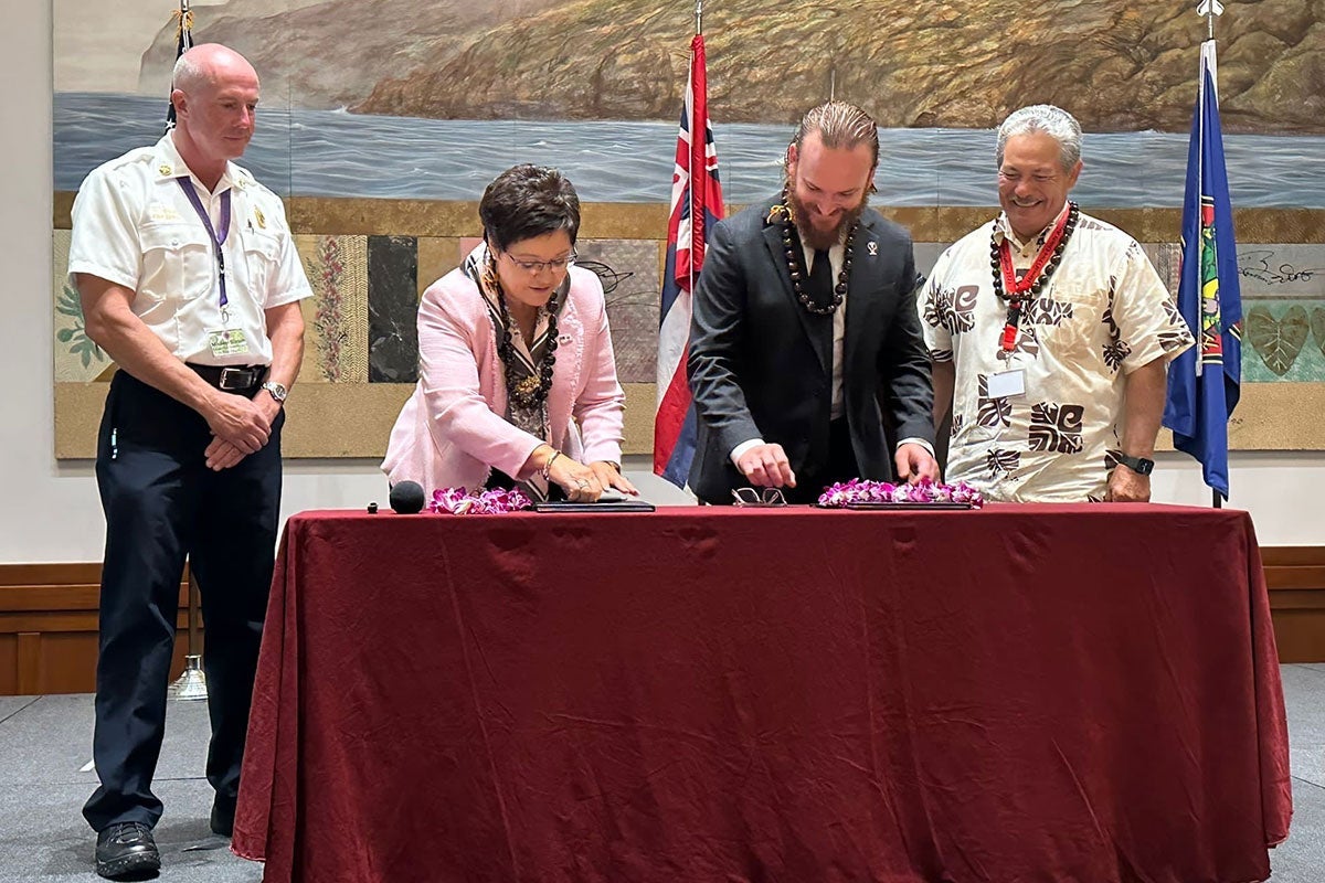 Four people behind a table with a dark red cloth draped over it