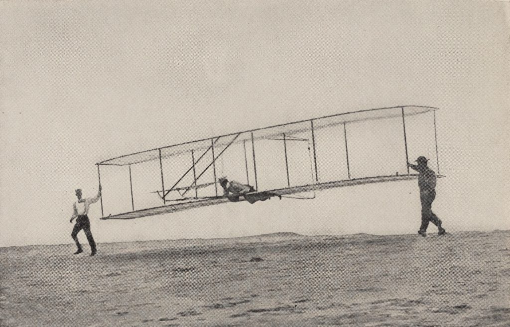 Glider test at Kitty Hawk, October 10, 1902. Orville is piloting the machine with Wilbur (left) and local resident Dan Tate (right). McFarland, Marvin W., ed. The Papers of Wilbur and Orville Wright. McGraw-Hill, 1953. View Source.