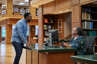 Male patron and reference librarian at front desk