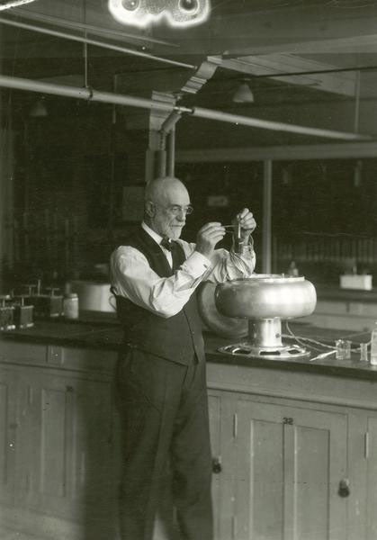 An older Stephen Babcock in his lab, standing by a centrifuge and demonstrating the butterfat milk test, undated photograph (wisconsinhistory.org)