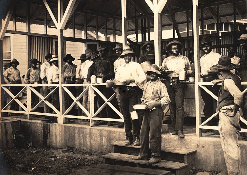 Meal time at an I.C.C. kitchen.
Canal Commission kitchens for silver payroll employees were outside, had no seating, and dispensed such poor quality food that many workers preferred to prepare their own meals over an open fire. View in Digital Collection »